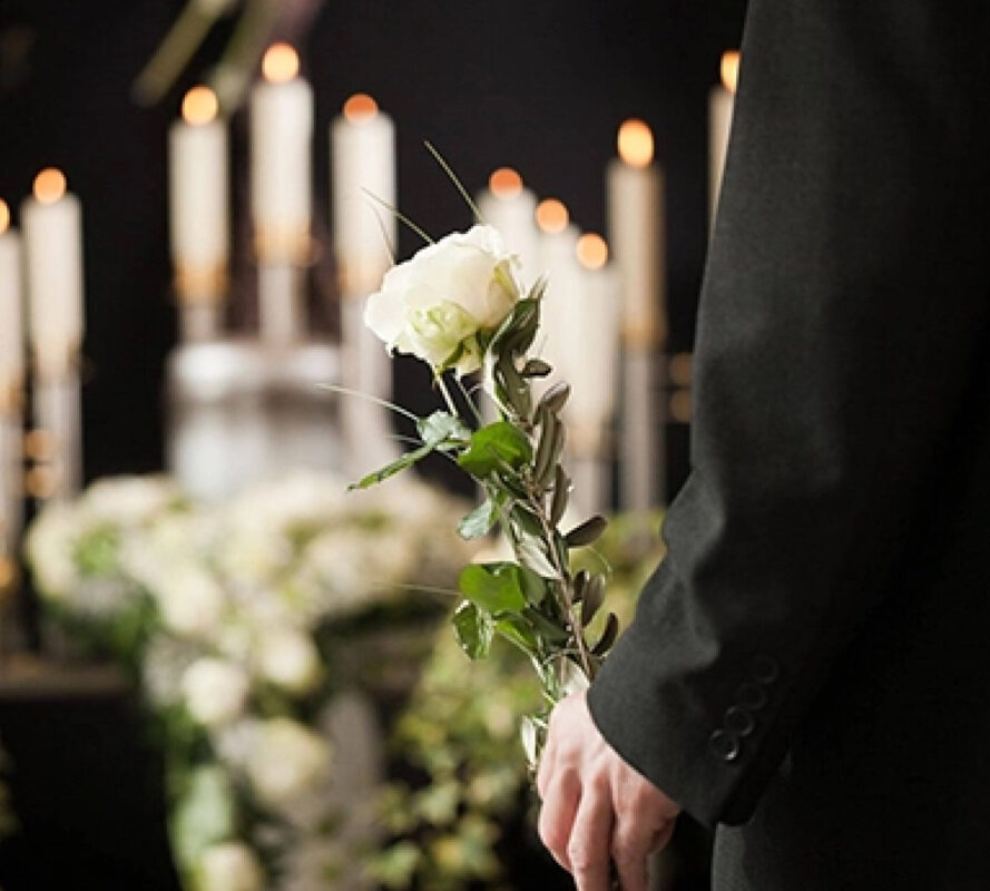Человек держит белую розу в здании для церемоний