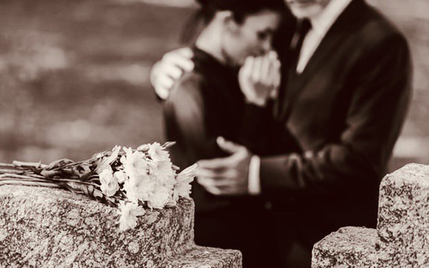 Женщина у могилы, мужчина её утешает